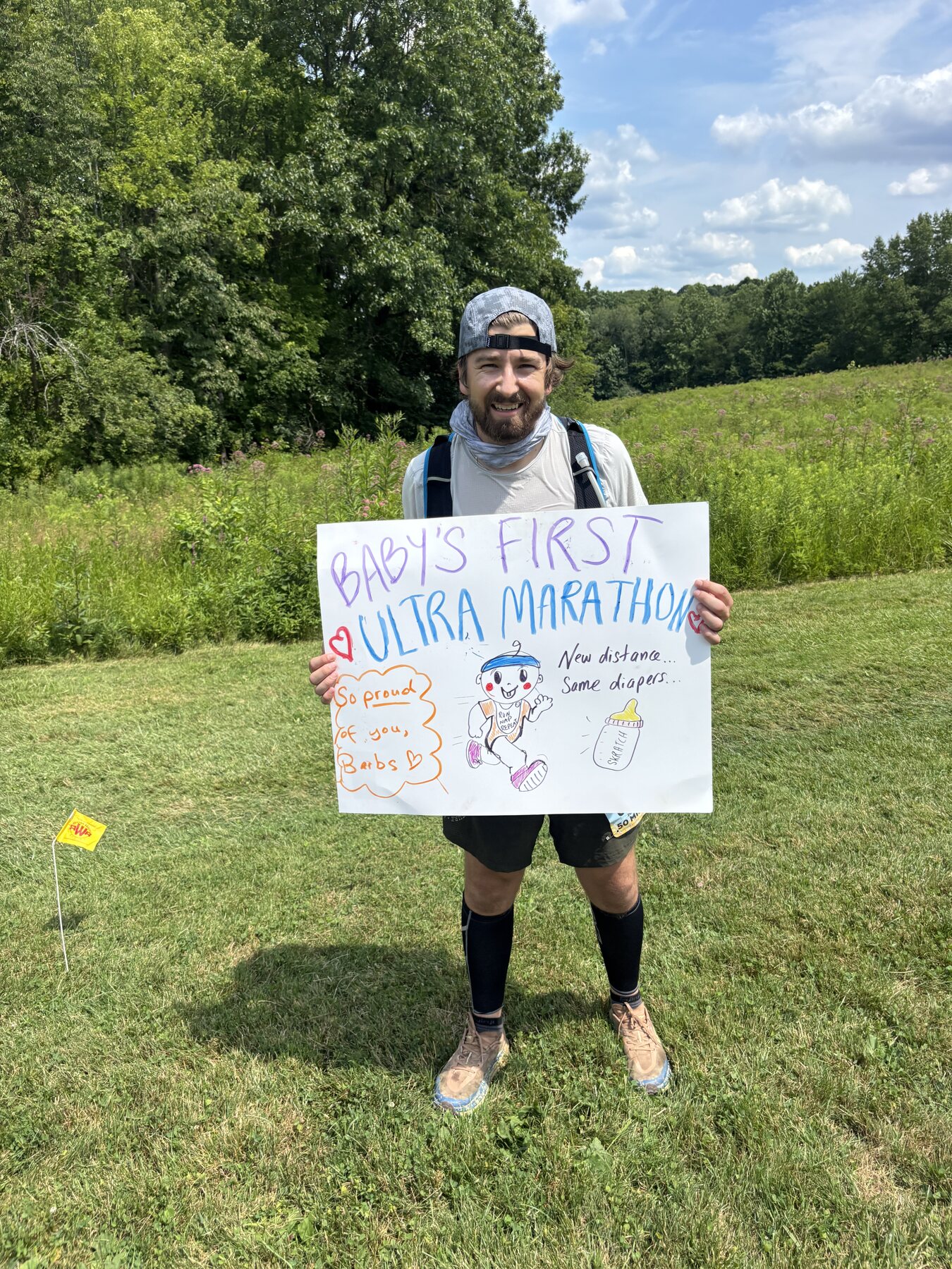 Holding a handmade first ultra marathon sign on the race course